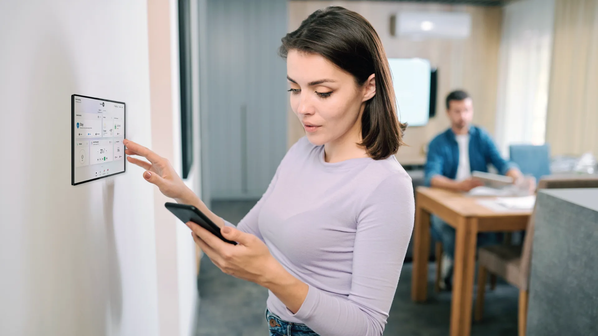 Blog-Featured-Image-1 Woman using control panel on wall and looking at phone